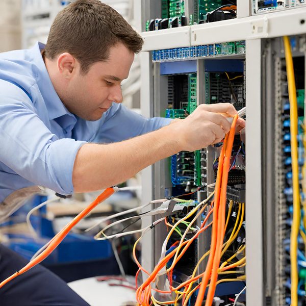 Total IT Corp technician running fiber-optic cabling in a server rack